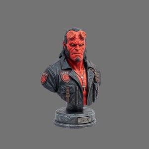 Può includere: Busto dettagliato del personaggio Hellboy, con pelle rossa, corna e giacca di pelle nera con toppe B.P.R.D. Il busto include una collana con croce ed è montato su una base in pietra con il nome "Hellboy".