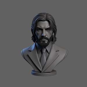 May include: A gray bust sculpture of a man with long hair, a beard, and a suit. The sculpture is detailed, with visible facial features and clothing details. The bust is mounted on a circular base.