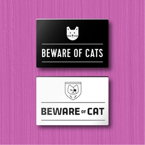 May include: Two black and white signs with a cat icon and the text "Beware of Cats" and "Beware of Cat".