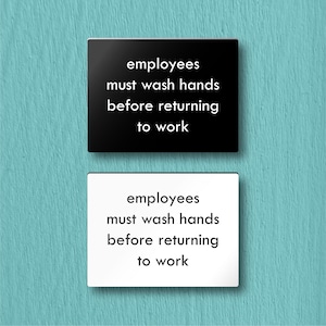 May include: Two signs, one black and one white, with the text "employees must wash hands before returning to work".