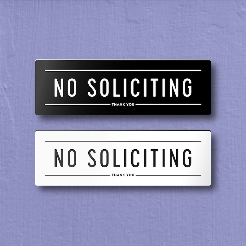 May include: Two signs, one black and one white, with the text "NO SOLICITING - THANK YOU" in bold, white letters.