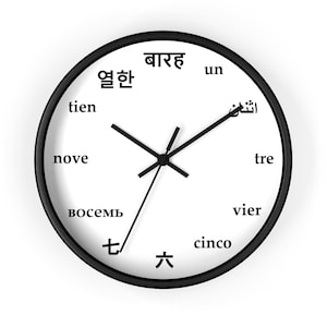 May include: A round wall clock with a black frame and a white face. The clock face features black hands and numerals in multiple languages, including English, Spanish, and Korean. The clock is a decorative item.