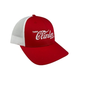 May include: A red and white trucker hat featuring the text "Think Clinton Mississippi" in white script. The hat has a red front and peak, with a white mesh back. A fashionable accessory.