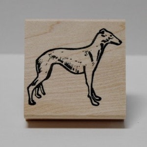 May include: A black and white line drawing of a greyhound dog on a wooden stamp.