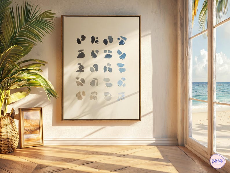 May include: A framed abstract art print featuring a series of blue and gray organic shapes on a cream background. The artwork is displayed on a white wall, with a wooden floor and a view of the ocean through a window.