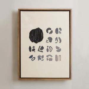 May include: A framed abstract painting with a black circle and various shapes in shades of blue and gray on a white background.