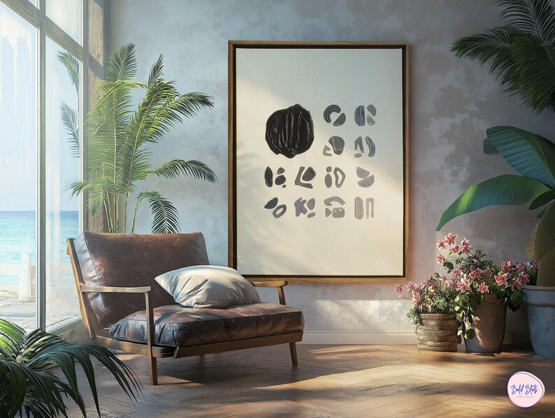 May include: A framed abstract art print with black and white shapes on a white background. The print is hanging on a light gray wall in a room with a brown leather armchair and plants.