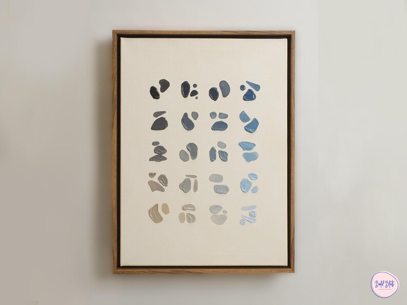 May include: Abstract art print featuring a series of organic shapes in shades of blue, gray, and beige, arranged in a grid pattern. The artwork is framed in a natural wood frame, creating a modern and minimalist aesthetic.