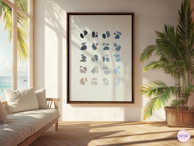 May include: A framed abstract art print featuring a series of blue and gray organic shapes on a white background. The artwork is displayed in a room with a wooden floor, a sofa, and a palm tree in a woven basket.