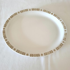 Peut inclure: Un plat ovale blanc avec un motif géométrique brun et or autour du bord.
