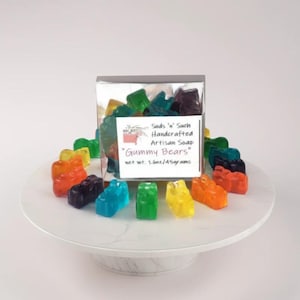 May include: A box of colorful handmade artisan soap bars shaped like gummy bears. The box is labeled "Suds 'n' Such Handcrafted Artisan Soap "Gummy Bears" net wt. 1.6oz/45grams".