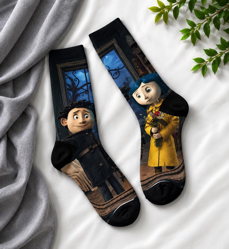 May include: A pair of black socks featuring characters from the animated film, "Coraline." One sock depicts a boy in a black coat, and the other shows a girl in a yellow coat holding flowers. The background includes a nighttime scene.