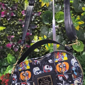 May include: A heart-shaped crossbody bag featuring a black and white comic-style print of characters from The Nightmare Before Christmas. The bag includes a black top handle, a detachable shoulder strap, and a gold-tone plaque reading JACK Loungefly.