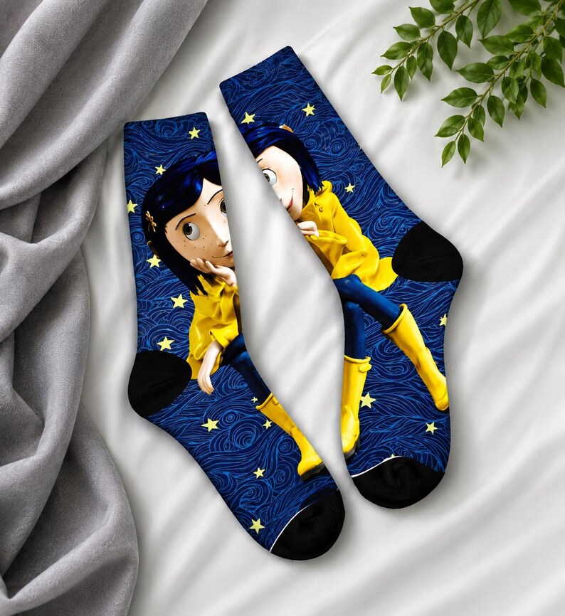 May include: A pair of crew socks featuring a cartoon character in a yellow coat and blue pants, set against a dark blue background with a swirling pattern and yellow stars. The socks have black heels and toes.