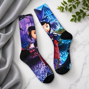May include: A pair of crew socks featuring a colorful graphic print. The socks display a scene from a movie, with a character in the foreground and a house in the background. The socks have black heels and toes.