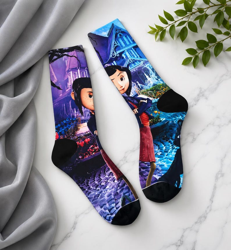 May include: A pair of crew socks featuring a colorful graphic print. The socks display a scene from a movie, with a character in the foreground and a house in the background. The socks have black heels and toes.