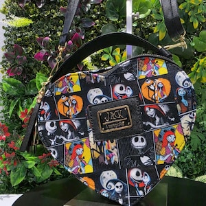 May include: A heart-shaped crossbody bag featuring a black background with a colorful collage print of characters from The Nightmare Before Christmas. The bag includes a black top handle, an adjustable shoulder strap, and a gold-toned Jack Loungefly logo.