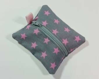Puede incluir: Una pequeña bolsa de cremallera gris con un patrón de estrellas rosas. La bolsa tiene un tirador de cremallera rosa.