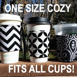 May include: Three different black and white patterned cup cozies. The cozies are made of fabric and fit all sizes of cups. The text "ONE SIZE COZY" is at the top of the image and the text "FITS ALL CUPS!" is at the bottom of the image.