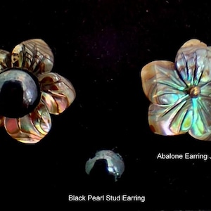 Pu&ograve; includere: Un orecchino a perno con perla nera e un copri-orecchino in abalone a forma di fiore a cinque petali. Il copri-orecchino presenta texture di conchiglia iridescenti e multicolori. Il testo B, Abalone Earring Jacket e Black Pearl Stud Earring &egrave; visibile.