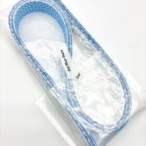 May include: A package containing a blue ribbon with white star patterns. The ribbon is labeled "Ast Blue Stars" and is 3/4" wide. The ribbon is in a clear plastic package.