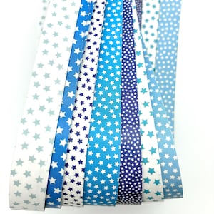 May include: A collection of blue and white patterned paper strips. The patterns include stars and dots in various shades of blue, from light to dark. The strips are arranged in a fan shape, showcasing the different designs.