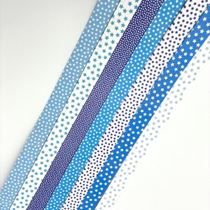 May include: An assortment of blue and white patterned ribbons with star designs. The ribbons vary in shades of blue, from light to dark, and feature different star patterns, including small dots and larger stars.
