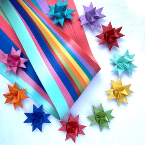 May include: A rainbow-colored paper strip with a variety of origami stars in different colors, including red, blue, green, yellow, and purple.