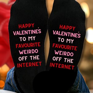 May include: A pair of black socks with pink and red lettering that reads "Happy Valentine's to my favourite weirdo off the internet".