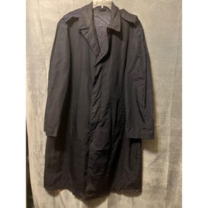 May include: A dark navy blue trench coat with a classic design. The coat features a notched collar, a double-breasted front, and a long length. The coat is made of a lightweight material and has a relaxed fit. The coat is hanging on a hanger.