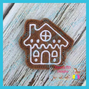 May include: A brown gingerbread house embroidery design with white stitching. The design features a chimney, a window, a door, and candy details.