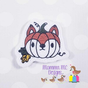 May include: Embroidered patch of a fox wearing a pumpkin hat with a brown, orange, and white color scheme. The patch is on a white background.
