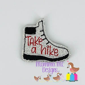 May include: A silver glitter boot with black trim and the words "Take a hike" in red embroidery.