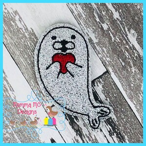 May include: A white and gray embroidered patch of a seal holding a red heart. The seal is smiling and has a cute expression.
