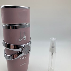 May include: A pink and silver perfume bottle with the word "YARA" and the brand name "Lattafa" printed on the bottle. A smaller, clear glass perfume bottle with a silver atomizer is also shown.