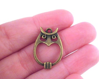 May include: A bronze owl charm with a cutout design. The owl has large eyes and a heart-shaped body.