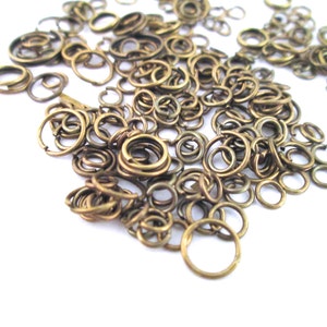 May include: A large pile of gold jump rings, a type of metal ring used in jewellery making.
