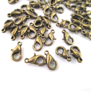 May include: A group of antique gold-toned metal lobster claw clasps. These clasps are commonly used for jewelry making and crafting.