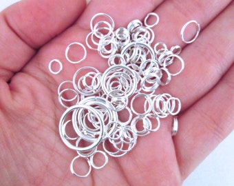 May include: A large pile of silver jump rings in various sizes, perfect for jewelry making.
