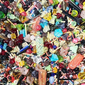 May include: A large assortment of colorful glass beads in various shapes and sizes. The beads are a mix of clear, opaque, and iridescent colors, including red, blue, green, yellow, and purple. The beads are perfect for jewelry making, crafts, and home decor.