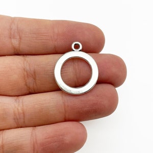 May include: Silver-toned metal circle pendant with a loop at the top. The pendant is about 1 inch in diameter.