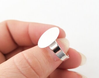 May include: A silver ring with a blank white oval-shaped bezel. The ring is adjustable and can be used to create custom jewellery.