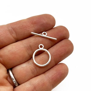 May include: Silver toggle clasp with a round ring. The clasp is made of metal and has a smooth finish.