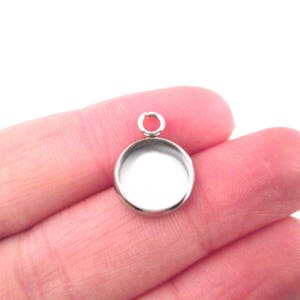Puede incluir: Pendiente de plata con una bisel redonda y en blanco para agregar un cabujón u otro adorno. El pendiente tiene un anillo de salto para sujetarlo a una cadena o cordón.