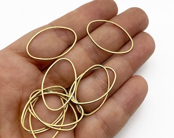 Può includere: Primo piano di una mano che tiene un mucchio di anelli ovali in ottone. Gli anelli hanno un diametro di circa 2,5 cm e una finitura liscia e lucida.