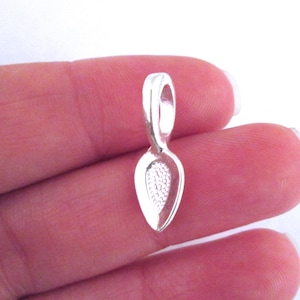 May include: Silver pendant bail with a teardrop shape and a loop at the top.