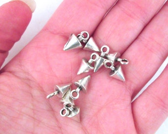 May include: A group of silver-toned metal pyramid-shaped charms with a loop at the top. The charms are scattered on a hand.