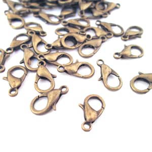 May include: A group of antique brass lobster claw clasps, a type of metal fastener used in jewelry making.