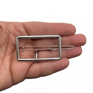 May include: Silver rectangle hair clip with a smooth finish. The clip has a simple design and is perfect for holding back hair.