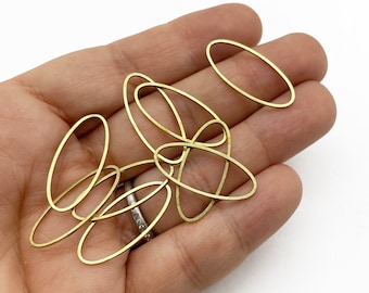 Può includere: Una collezione di anelli ovali in metallo dorato. Gli anelli sono disposti in una pila su una mano.